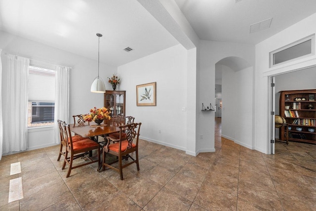 dining area with baseboards, visible vents, and arched walkways