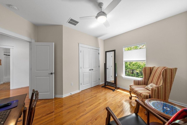 living area with visible vents, light wood finished floors, baseboards, and ceiling fan
