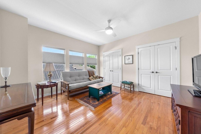 living area featuring light wood-style floors and a ceiling fan