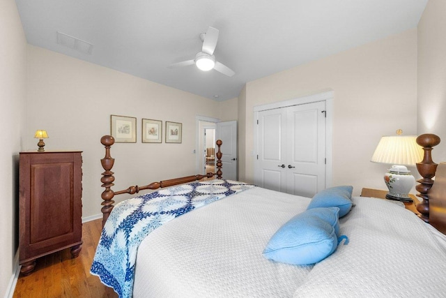 bedroom featuring wood finished floors, visible vents, a closet, baseboards, and ceiling fan