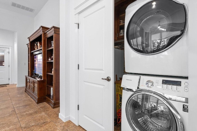 laundry area with baseboards, stacked washer and dryer, laundry area, and visible vents