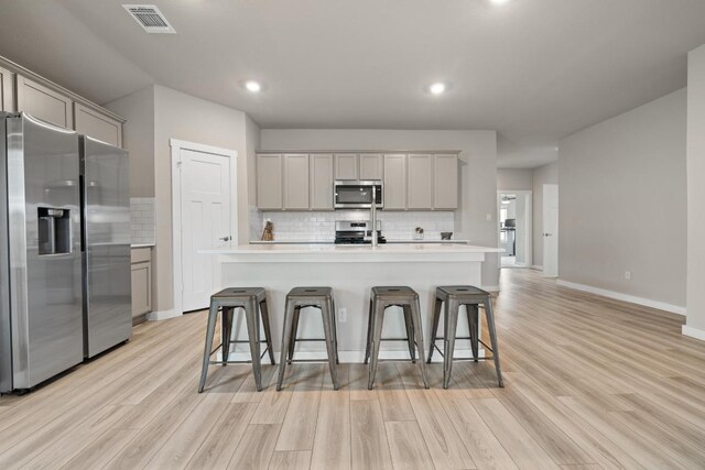 kitchen with backsplash, gray cabinetry, stainless steel appliances, and visible vents