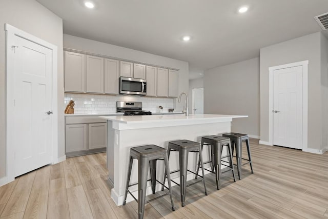 kitchen featuring light wood-type flooring, stainless steel appliances, and gray cabinetry