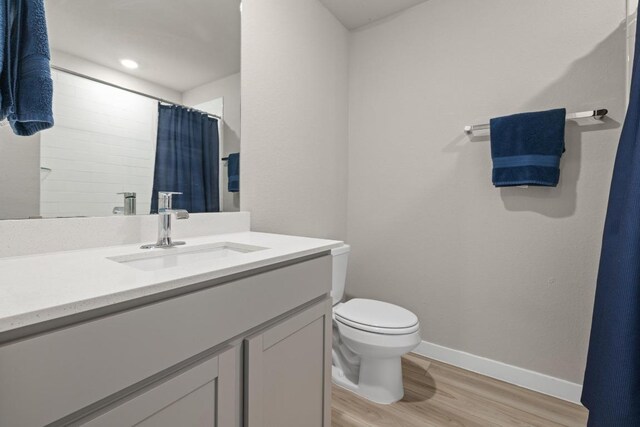full bath featuring toilet, wood finished floors, vanity, baseboards, and a shower with shower curtain