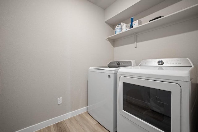 clothes washing area with baseboards, light wood-style flooring, laundry area, and independent washer and dryer