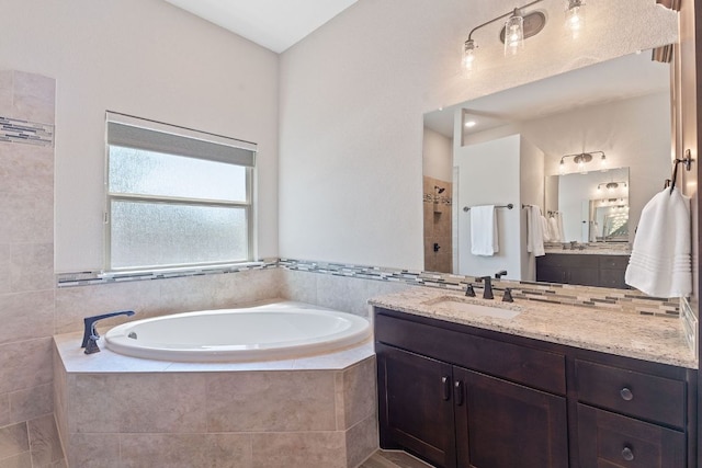full bath featuring a tile shower, a bath, and vanity