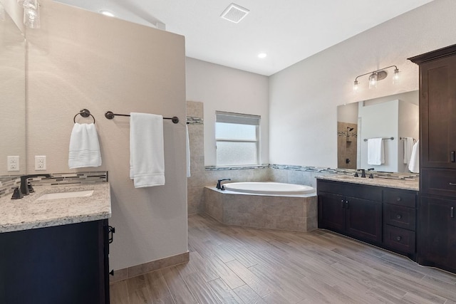bathroom with a garden tub, a sink, two vanities, visible vents, and tiled shower