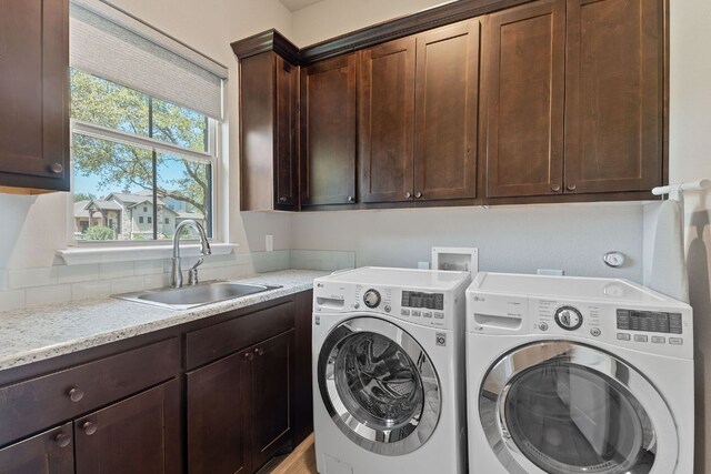 washroom with cabinet space, washing machine and clothes dryer, and a sink