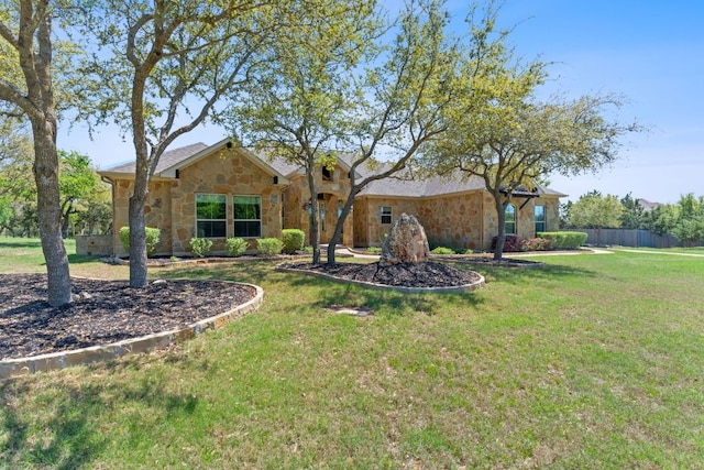 exterior space with a lawn, stone siding, and fence