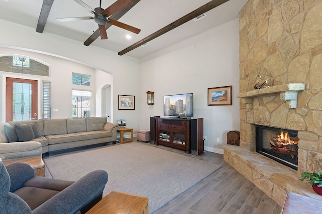 101 Dakota Dr, Georgetown, TX 78633 - living room featuring beam ceiling, a stone fireplace, wood finished floors, a ceiling fan, and a towering ceiling