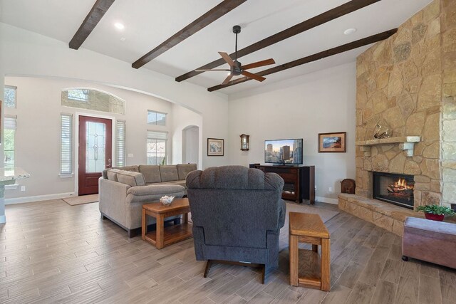living area with a ceiling fan, baseboards, beam ceiling, and a fireplace