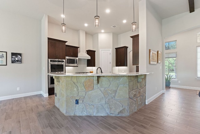 kitchen featuring dark brown cabinets, light wood-style flooring, backsplash, appliances with stainless steel finishes, and visible vents