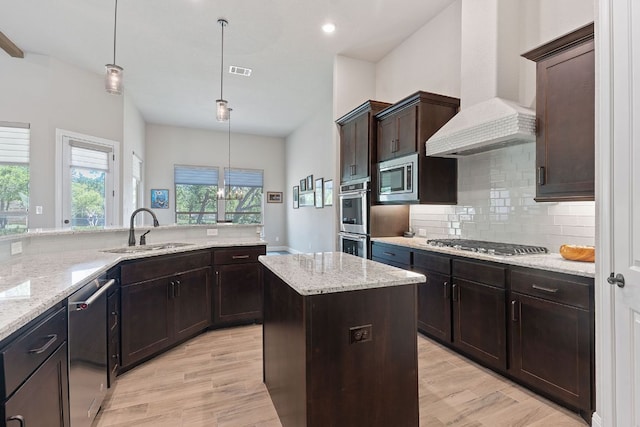 kitchen featuring a sink, stainless steel appliances, light wood-style flooring, premium range hood, and visible vents