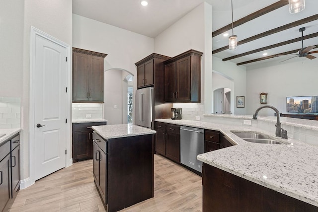 kitchen with decorative backsplash, stainless steel appliances, a sink, and arched walkways