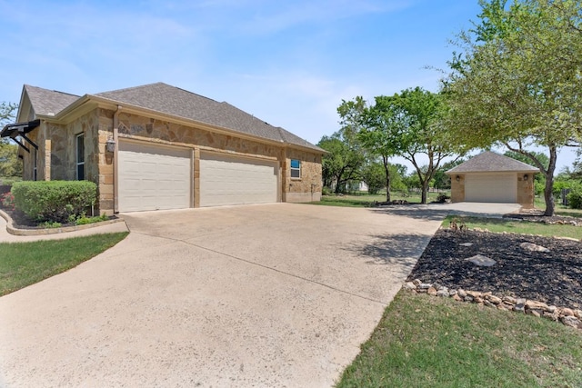 view of side of property featuring stone siding, an attached garage, a shingled roof, and driveway