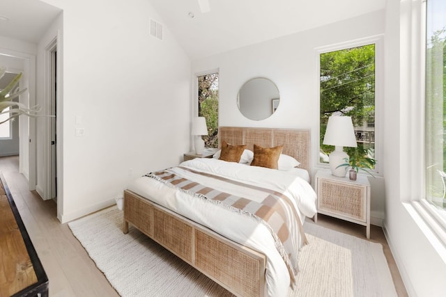 bedroom featuring radiator heating unit, multiple windows, light wood-type flooring, and visible vents