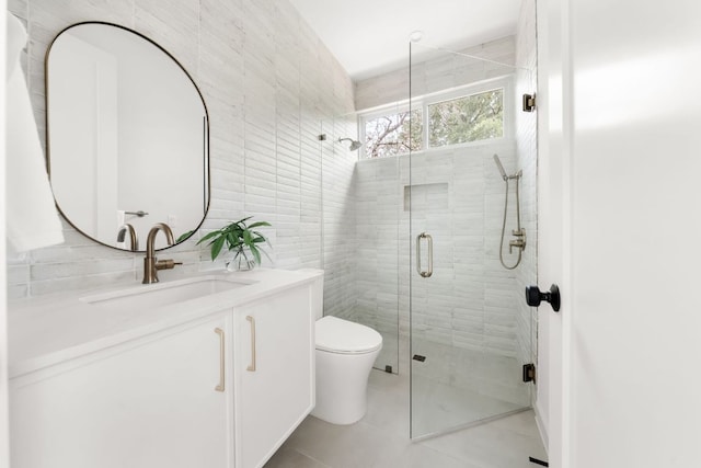 bathroom featuring vanity, tile patterned flooring, toilet, tile walls, and a stall shower