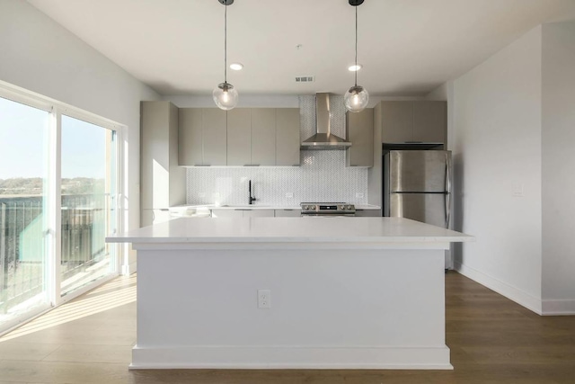 kitchen with tasteful backsplash, light countertops, wall chimney exhaust hood, appliances with stainless steel finishes, and gray cabinetry