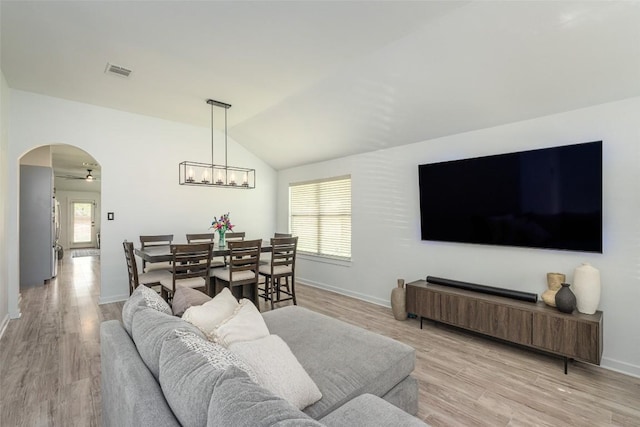 129 Aguilar Dr, Hutto, TX 78634 - living room with arched walkways, lofted ceiling, light wood finished floors, ceiling fan, and a chandelier