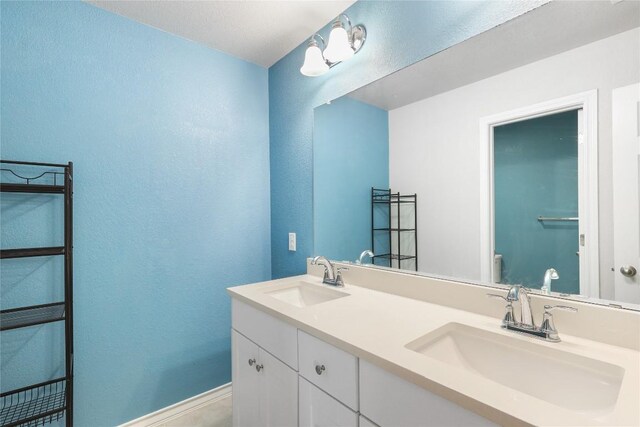 345 Coba St, Leander, TX 78641 - full bath with double vanity, a textured wall, toilet, and baseboards