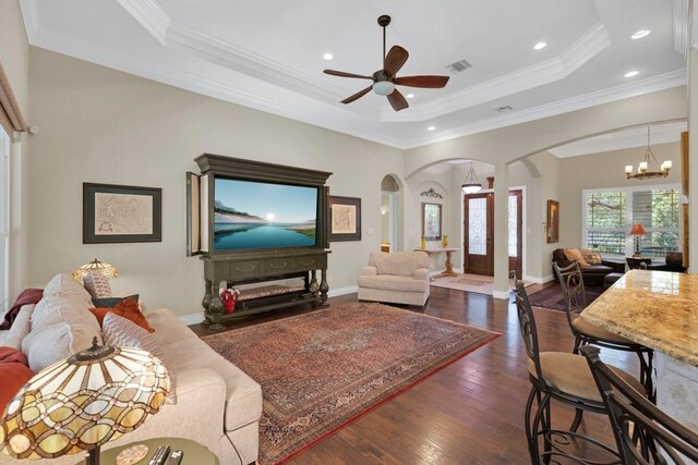 1164 Fairway Dr, Canyon Lake, TX 78133 - living area with dark wood-type flooring, crown molding, a tray ceiling, arched walkways, and ceiling fan with notable chandelier