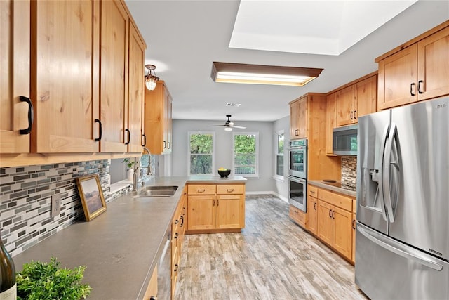 104 Tonkawa Cv, Kyle, TX 78640 - kitchen featuring light wood finished floors, a peninsula, a sink, tasteful backsplash, and appliances with stainless steel finishes