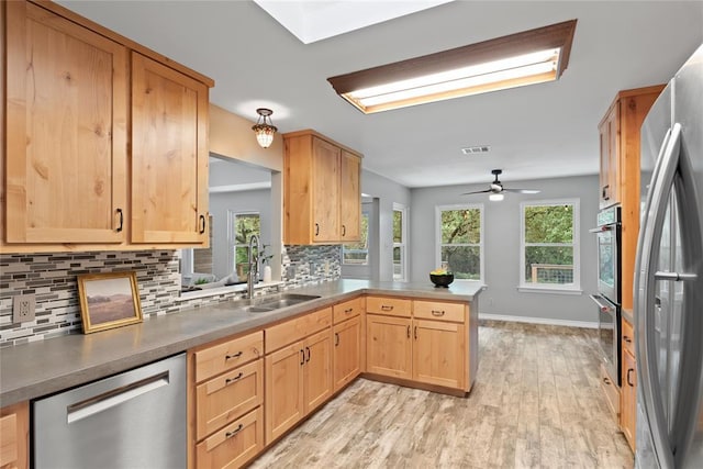104 Tonkawa Cv, Kyle, TX 78640 - kitchen with light wood-style flooring, a sink, plenty of natural light, backsplash, and appliances with stainless steel finishes