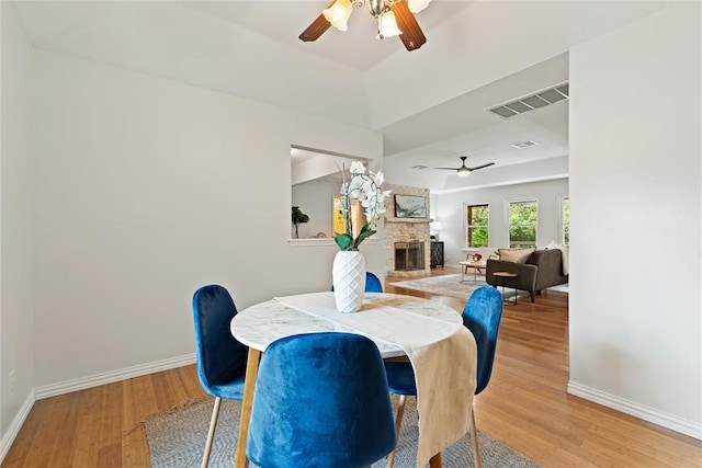 104 Tonkawa Cv, Kyle, TX 78640 - dining area with light wood-type flooring, visible vents, a fireplace, and ceiling fan