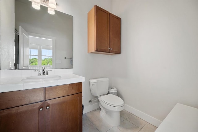 bathroom with toilet, vanity, tile patterned floors, and baseboards