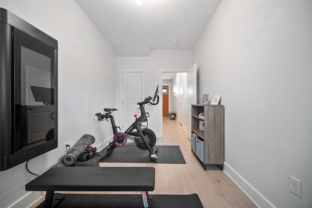 exercise area with baseboards and light wood-type flooring