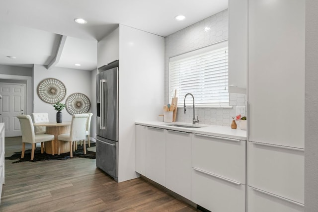 kitchen featuring white cabinets, light countertops, backsplash, a sink, and high end refrigerator