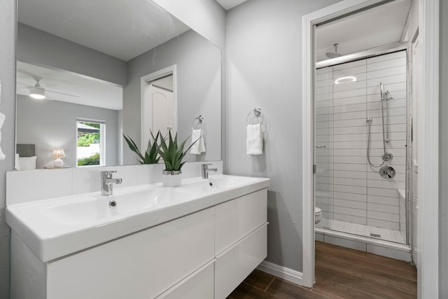 full bath with wood finished floors, a sink, double vanity, and a stall shower
