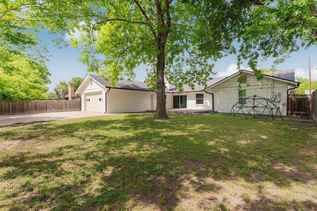 view of front of property with a front lawn, concrete driveway, fence, brick siding, and an attached garage