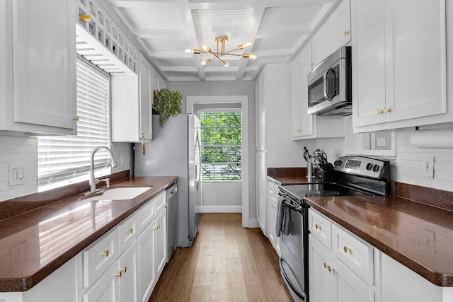3212 Darnell Dr, Austin, TX 78745 - kitchen featuring stainless steel appliances, light wood-type flooring, a chandelier, white cabinets, and beamed ceiling