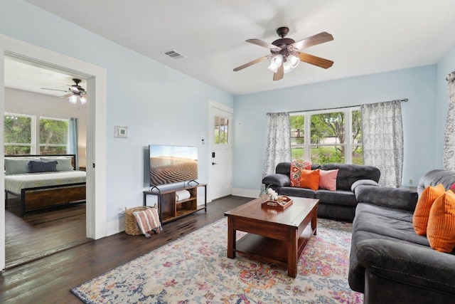 living area featuring baseboards, a ceiling fan, wood finished floors, and visible vents