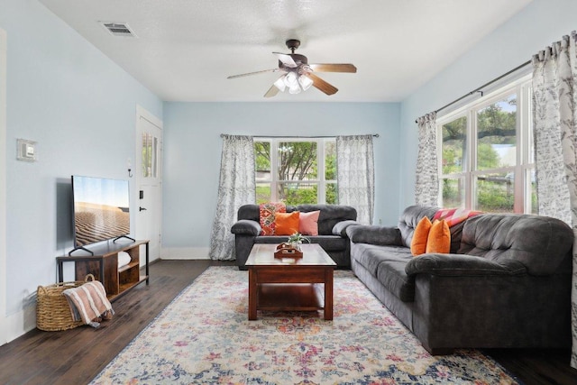 living area with a wealth of natural light, a ceiling fan, wood finished floors, and visible vents