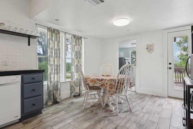 dining room featuring a textured ceiling, visible vents, light wood finished floors, and a wealth of natural light