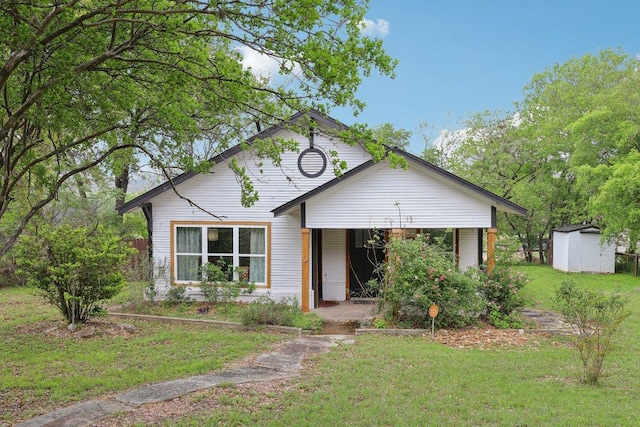 view of front facade with a front lawn, an outbuilding, and a storage shed