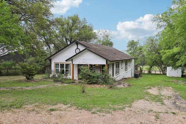 bungalow-style house with a front lawn, fence, an outbuilding, and a storage shed