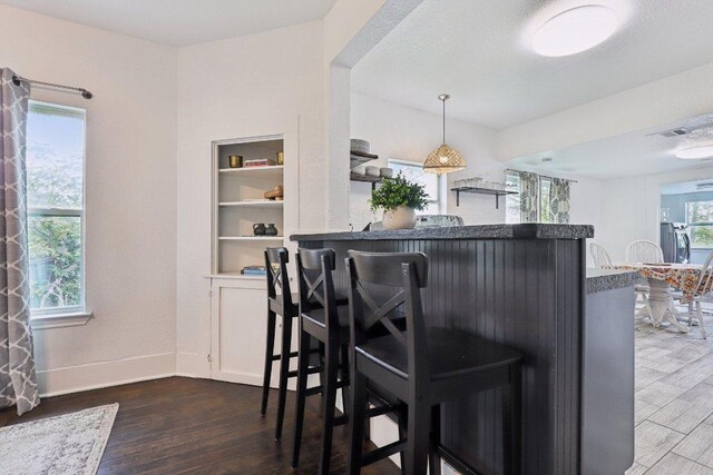 dining space featuring wood finished floors, visible vents, built in shelves, and baseboards