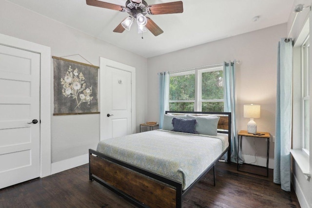 bedroom featuring dark wood-type flooring, a ceiling fan, and baseboards