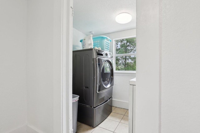 washroom featuring light tile patterned flooring, a textured ceiling, and laundry area
