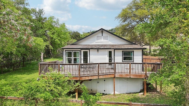 rear view of house with a lawn, fence, and a deck