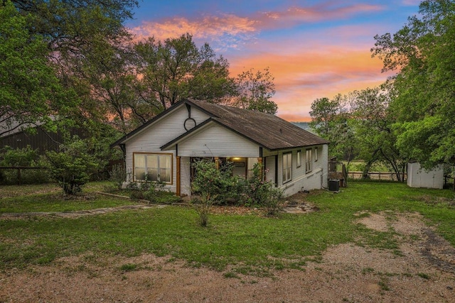 view of front of home featuring an outbuilding, a front lawn, central AC unit, fence, and a shed