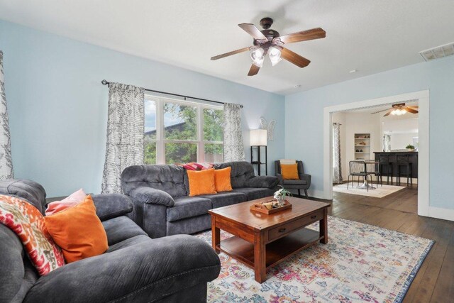 living room featuring baseboards, visible vents, a ceiling fan, and hardwood / wood-style flooring