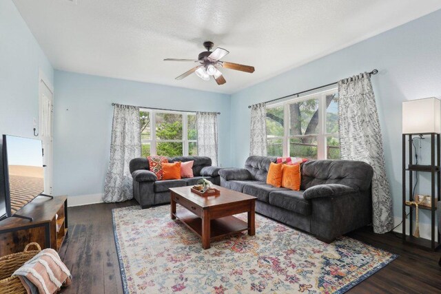 living area featuring wood finished floors, a ceiling fan, and baseboards