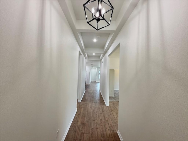 corridor with baseboards, dark wood-type flooring, and an inviting chandelier