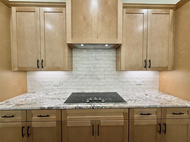 kitchen with black electric cooktop, light stone countertops, and decorative backsplash