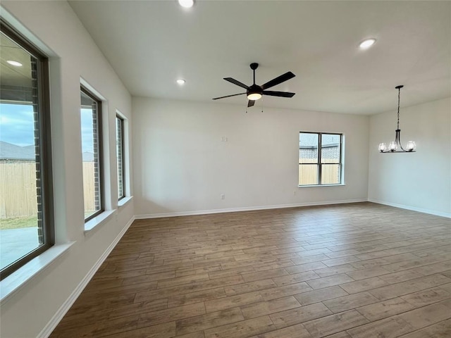 empty room with recessed lighting, baseboards, dark wood-style flooring, and ceiling fan with notable chandelier