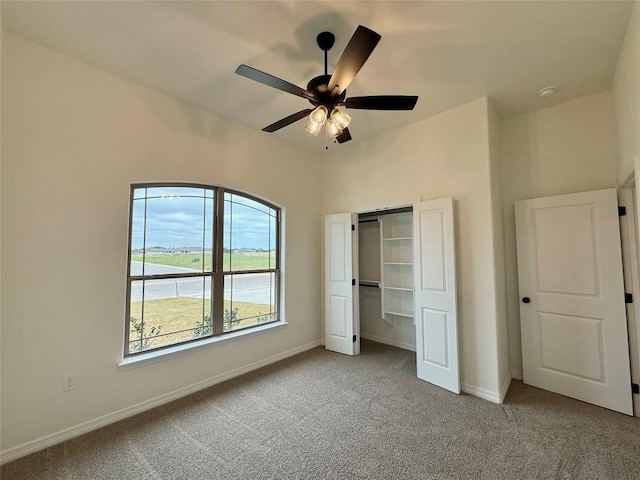 unfurnished bedroom featuring a ceiling fan, carpet floors, a closet, and baseboards